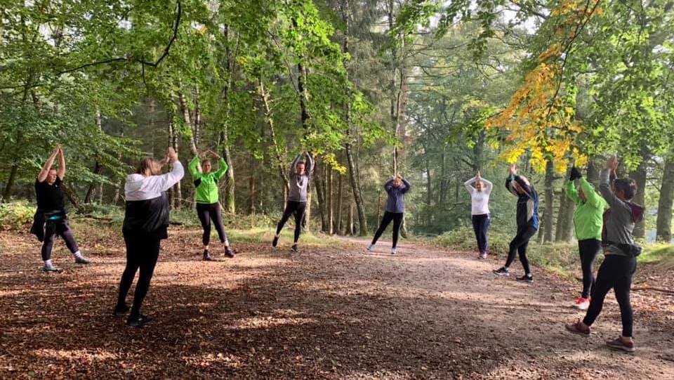 Een groep aan het sporten in een bos met herfstkleuren.